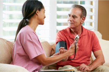 elderly woman monitoring elderly man's blood pressure