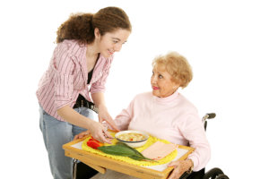 caregiver and elderly woman giving her meal